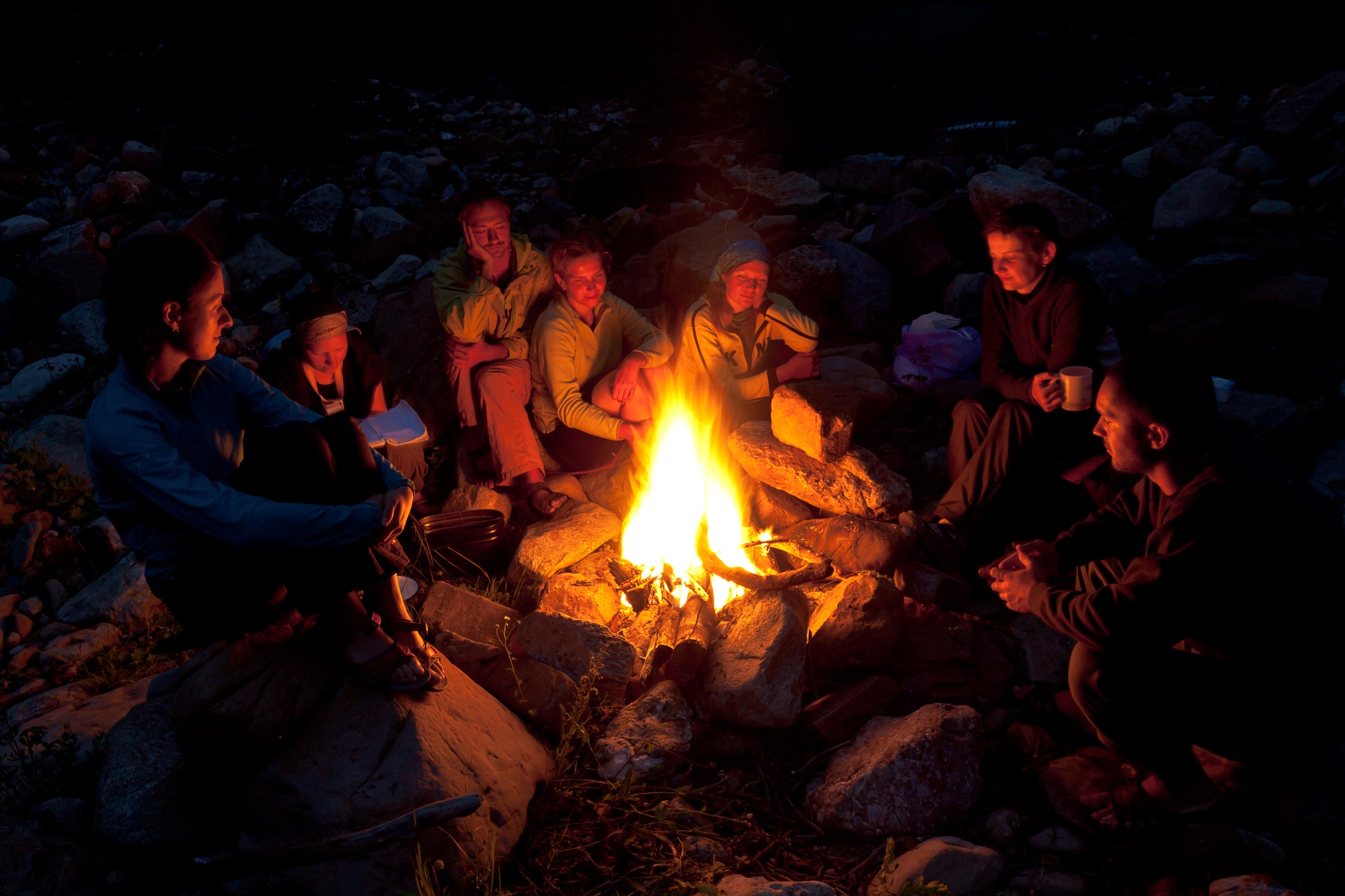 Friends gathered around a bonfire at night